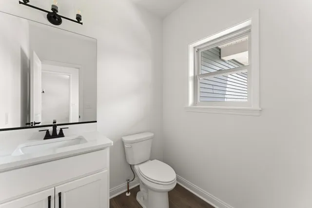 a bathroom with a toilet sink vanity and mirror