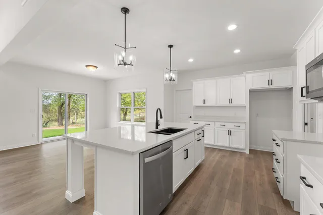 a kitchen with stainless steel appliances granite countertop a sink stove and white cabinets with wooden floor