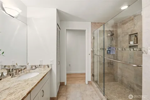 a bathroom with a granite countertop sink mirror and shower