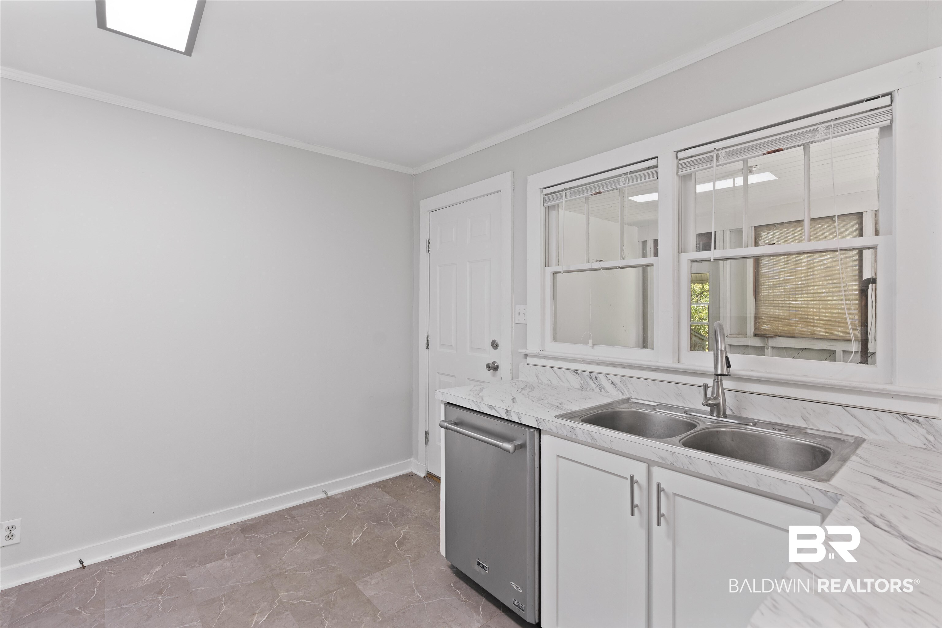 2126 Barron Place Mobile, AL 36605 - Photo 12 of 33 Kitchen with ornamental molding, stainless steel dishwasher, sink, tile patterned floors, and white cabinets