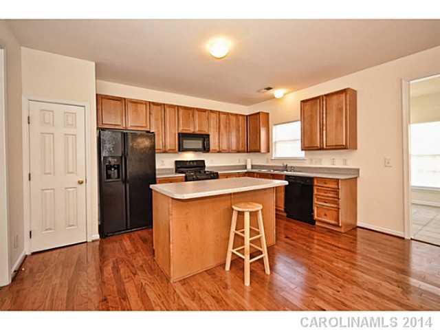 5028 Prosperity Ridge Road, Unit 5028 Charlotte, NC 28269 - Photo 5 of 16 a kitchen with stainless steel appliances granite countertop a refrigerator a sink dishwasher a stove with wooden cabinets and wooden floor