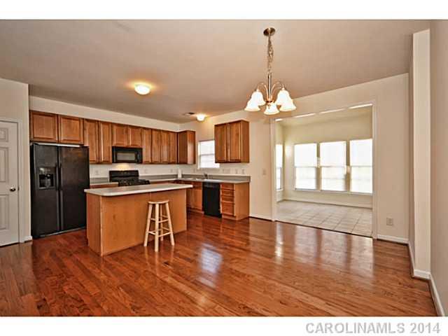 5028 Prosperity Ridge Road, Unit 5028 Charlotte, NC 28269 - Photo 7 of 16 a kitchen with stainless steel appliances kitchen island granite countertop a refrigerator a stove a sink dishwasher with a dining table and chairs