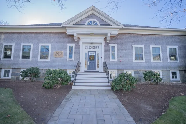 a view of a brick house with many windows and a yard