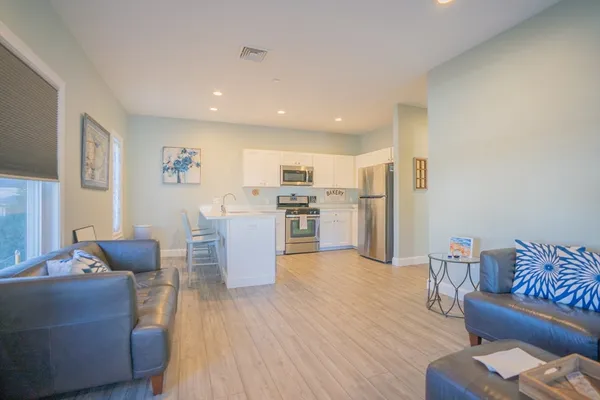a living room with furniture wooden floor and a kitchen view