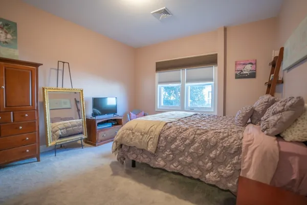 a bed sitting in a bedroom next to a window and dresser