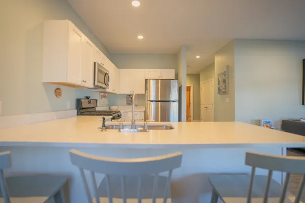 a kitchen with stainless steel appliances kitchen island granite countertop a table chairs and a refrigerator