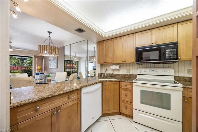 a kitchen with granite countertop white cabinets stainless steel appliances and a counter space