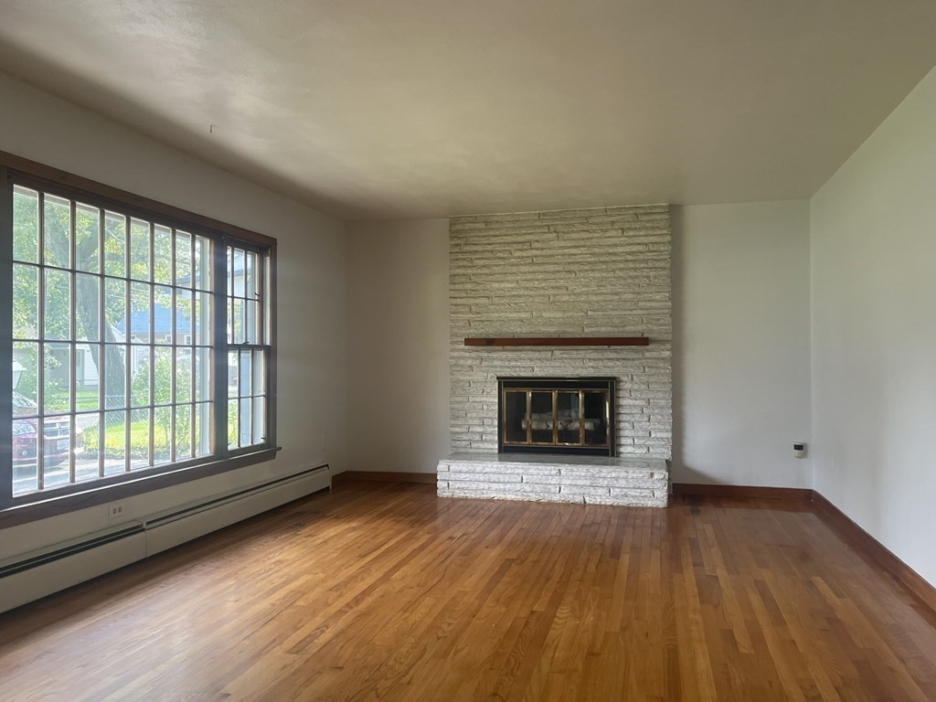 631 Allen Street Springfield, MA 01118 - Photo 2 of 15 an empty room with wooden floor fireplace and windows
