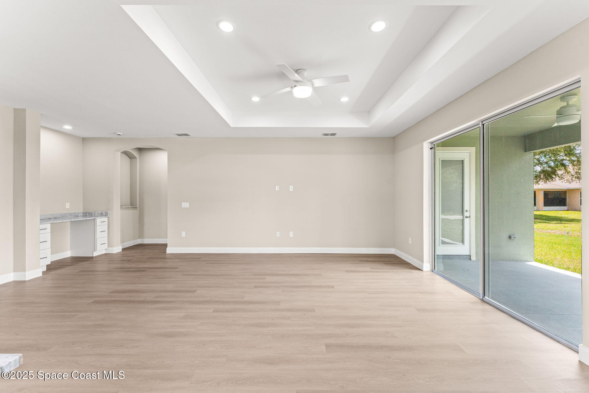 241 Sarah Road Southwest Palm Bay, FL 32908 - Photo 15 of 54 a view of an empty room with wooden floor and a kitchen