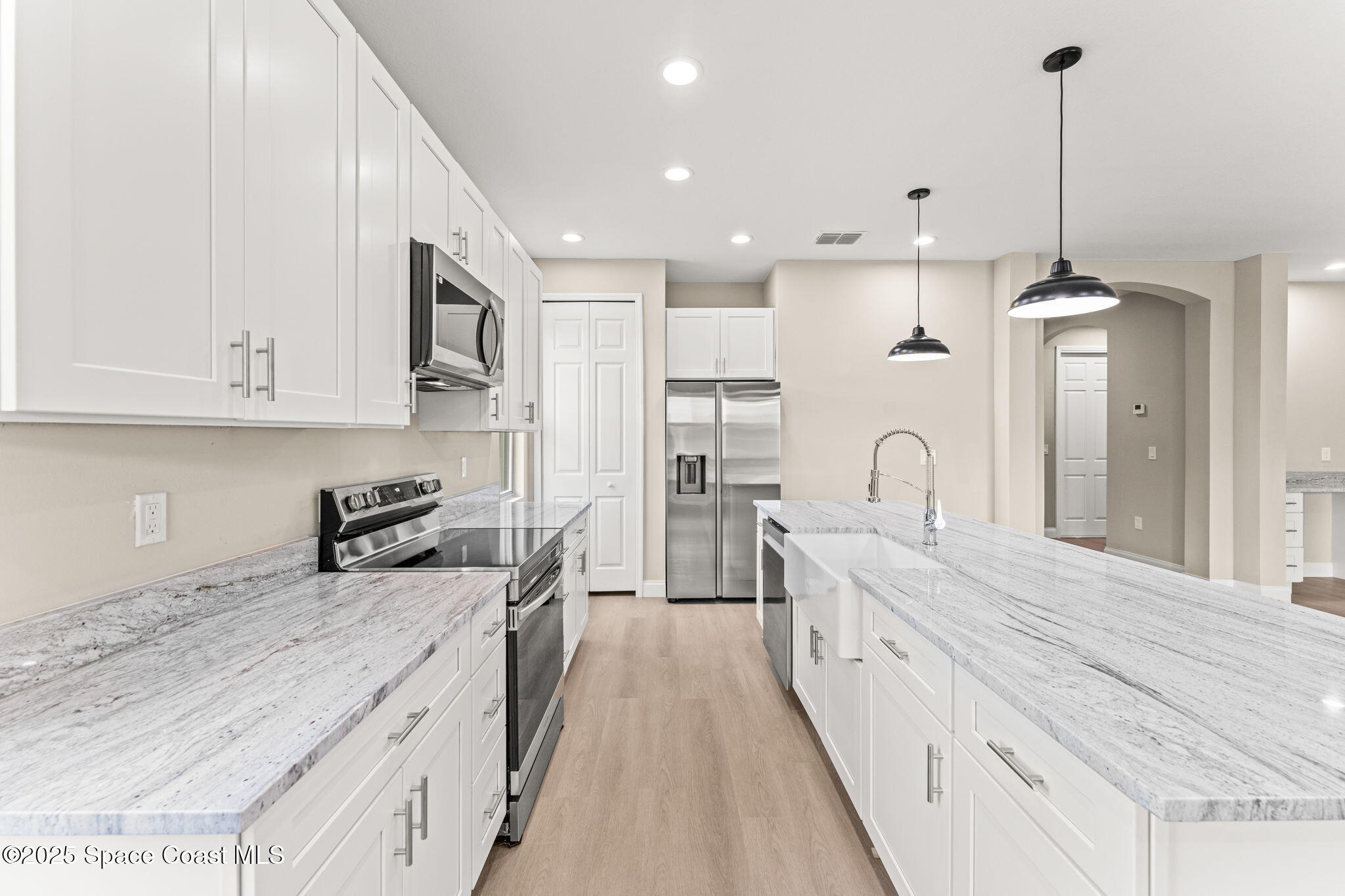 241 Sarah Road Southwest Palm Bay, FL 32908 - Photo 18 of 54 a large kitchen with stainless steel appliances kitchen island granite countertop a stove a sink a refrigerator and white cabinets with wooden floor