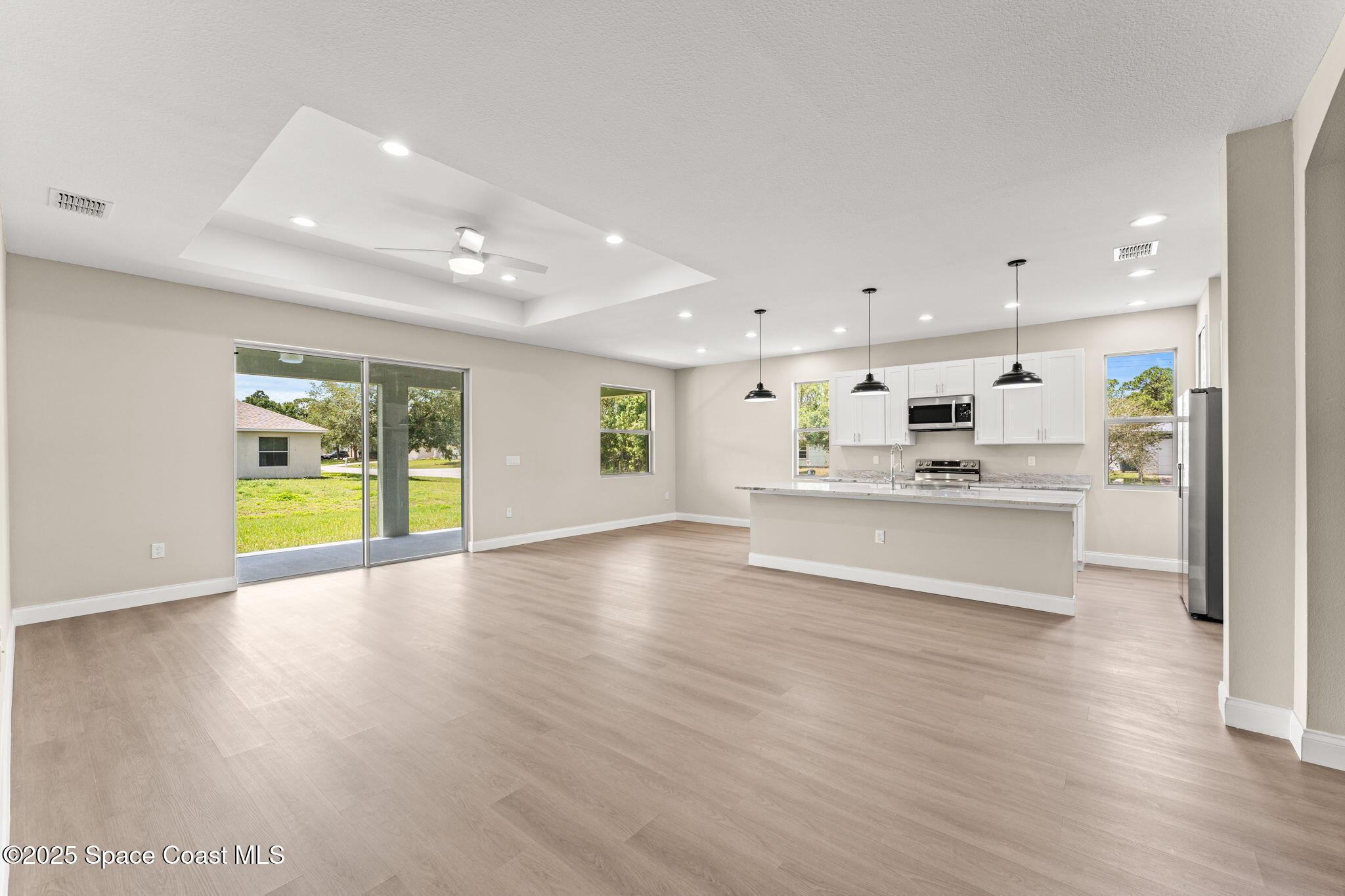 241 Sarah Road Southwest Palm Bay, FL 32908 - Photo 9 of 54 a large white kitchen with kitchen island a island a stove a wooden floor and a sink