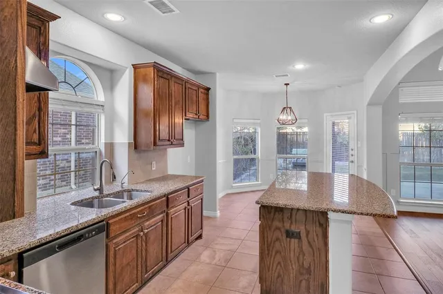 a kitchen with stainless steel appliances granite countertop a sink dishwasher stove top oven and refrigerator