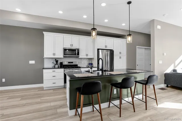 a kitchen with stainless steel appliances kitchen island granite countertop a stove a sink and a refrigerator