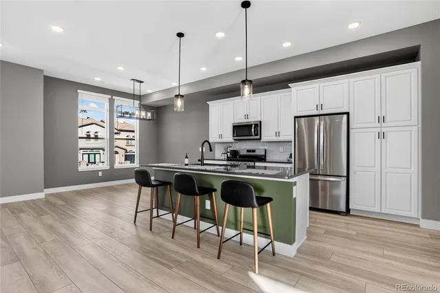 a kitchen with stainless steel appliances granite countertop a table chairs refrigerator and microwave