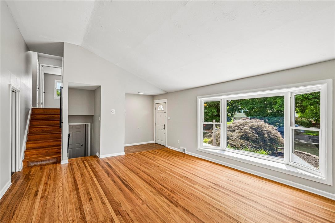 2428 Nottingham Road Bethlehem, PA 18017 - Photo 7 of 48 Hardwood floors stretch across this living area, featuring a broad bay window that frames views of the lush outdoor greenery.