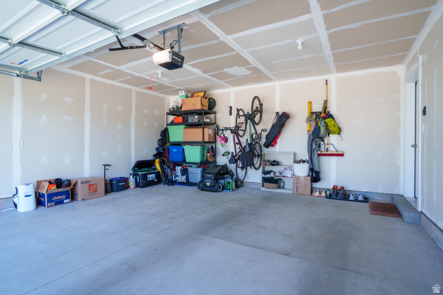 1486 West 2055th Street South Logan, UT 84339 - Photo 33 of 45 Spacious garage featuring concrete flooring, a ceiling-mounted garage door opener, and wall-mounted storage solutions