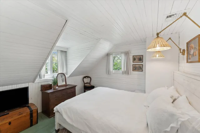 a bedroom with a bed a flat screen tv and dresser