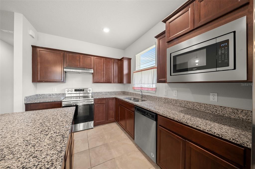 5947 Southwest 93rd Circle Ocala, FL 34481 - Photo 11 of 32 a kitchen with stainless steel appliances granite countertop a sink stove and microwave