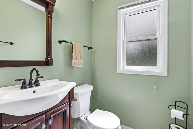 455 Elmhurst Road Mount Prospect, IL 60056 - Photo 9 of 19 a bathroom with a toilet a sink and mirror