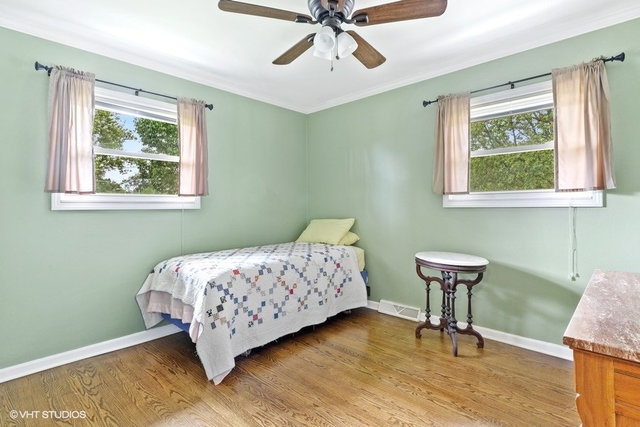 455 Elmhurst Road Mount Prospect, IL 60056 - Photo 10 of 19 a bedroom with a bed and a chandelier