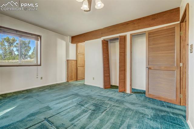 23555 Murphy Road Calhan, CO 80808 - Photo 35 of 49 Unfurnished bedroom featuring carpet floors, an inviting chandelier, and two closets