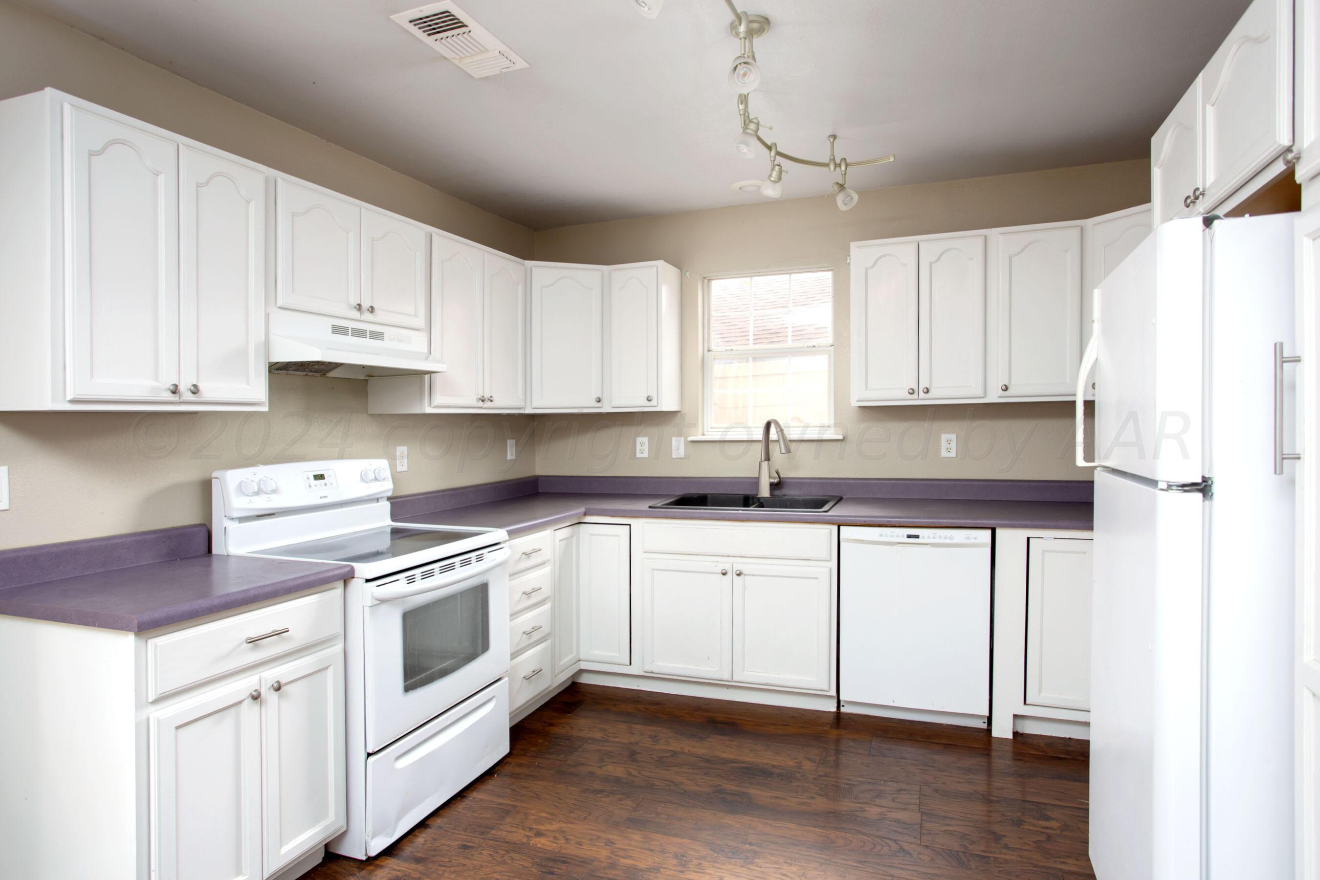 4205 South Ong Street Amarillo, TX 79110 - Photo 9 of 25 a kitchen with granite countertop white cabinets and white appliances