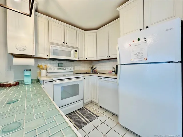 a kitchen with white cabinets and white appliances
