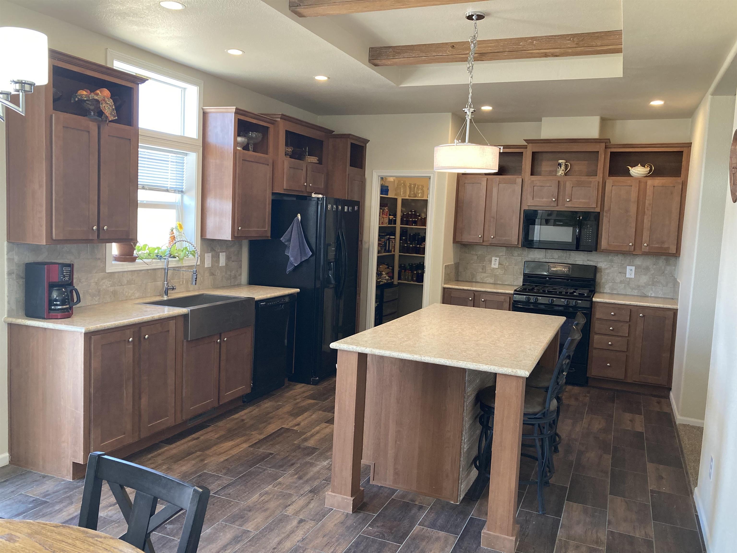 2413 1300th Road Delta, CO 81416 - Photo 8 of 35 a kitchen with stainless steel appliances kitchen island granite countertop a refrigerator a sink dishwasher a stove and a dining table with wooden floor