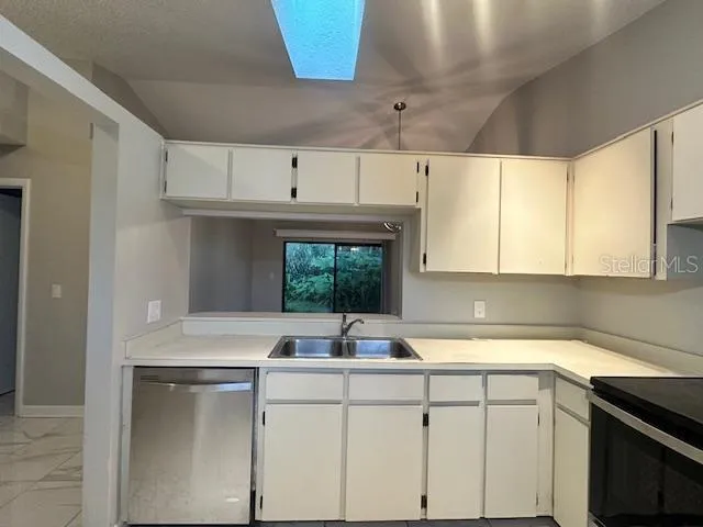 a kitchen with cabinets appliances a sink and a window