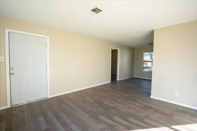 a view of an empty room with wooden floor and closet