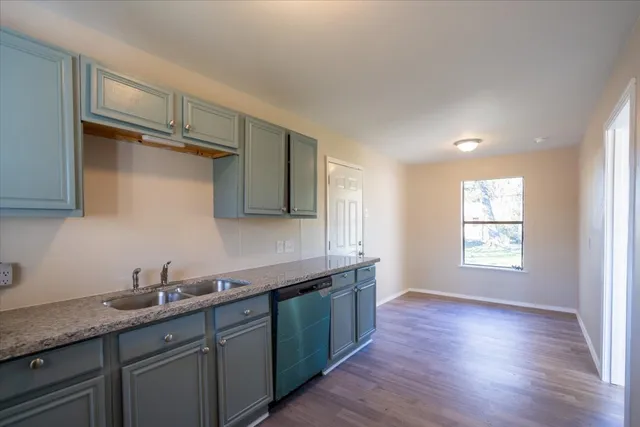a kitchen with granite countertop a sink a stove and cabinets
