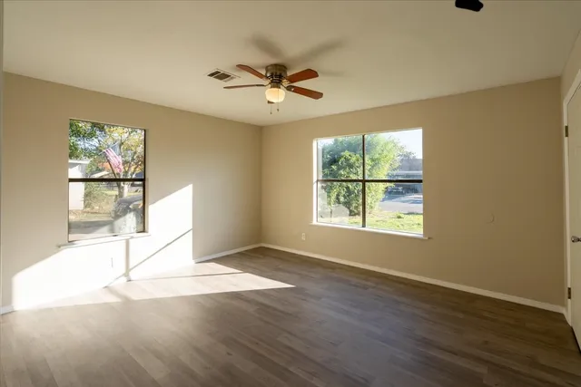 an empty room with wooden floor and windows