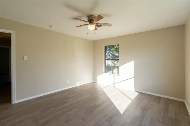 an empty room with wooden floor and a ceiling fan