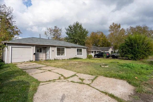 a view of a yard in front of a house with a large tree