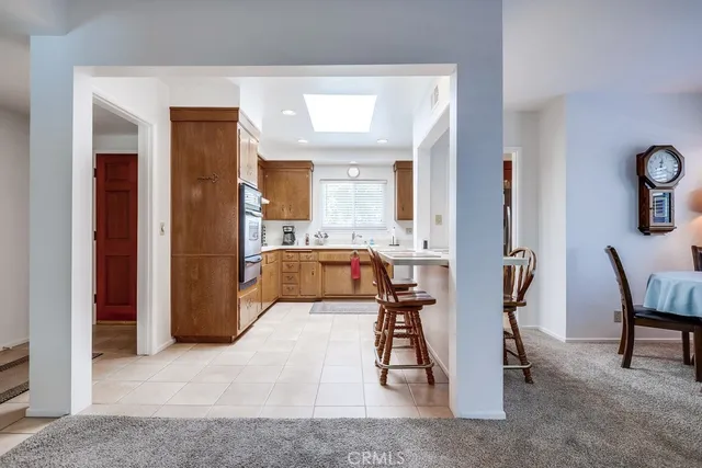 a dining room with stainless steel appliances kitchen island granite countertop a table chairs and a refrigerator