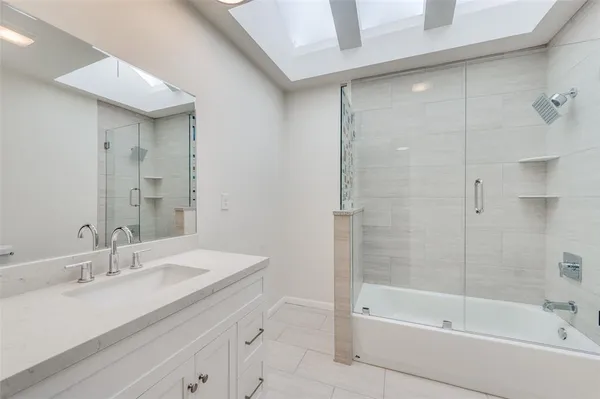 a bathroom with a bathtub shower sink vanity and a mirror