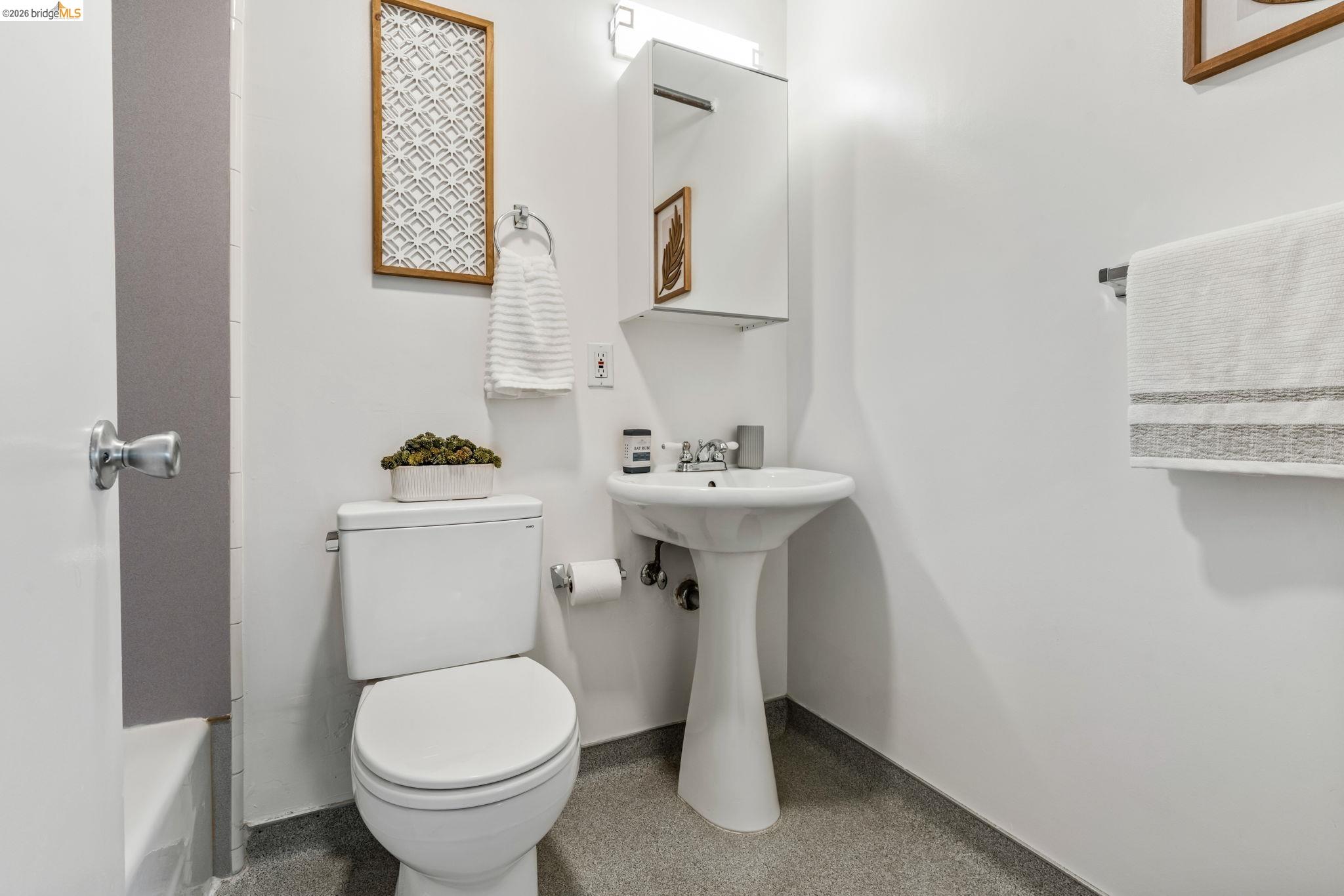1920 Union Street, Unit 9 Oakland, CA 94607 - Photo 26 of 35 Pedestal sink with chrome faucet, white toilet, and gray flooring