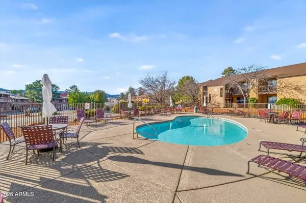 a swimming pool with outdoor seating and covered with trees