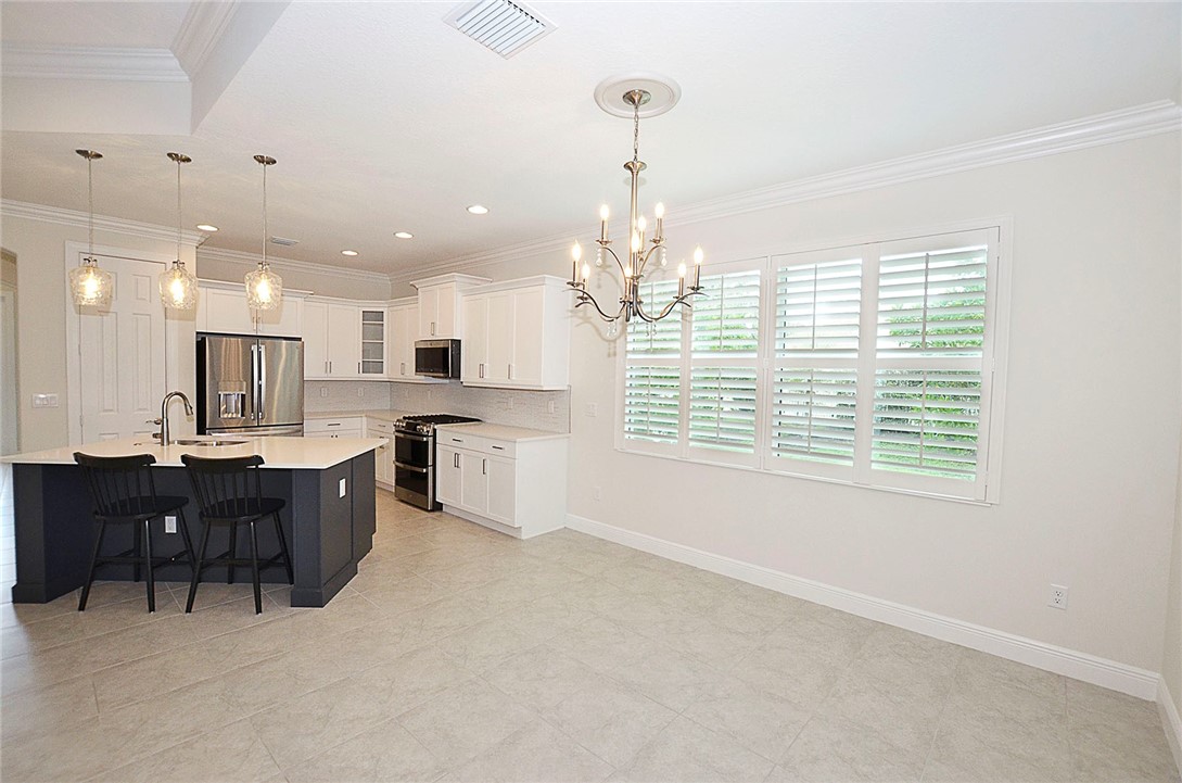 6145 Bella Rosa Lane Vero Beach, FL 32966 - Photo 8 of 36 a large kitchen with kitchen island a sink stainless steel appliances and a chandelier