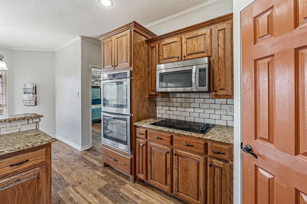 112 Blue Ribbon Lane Stephenville, TX 76401 - Photo 12 of 31 a kitchen with granite countertop a stove microwave and refrigerator