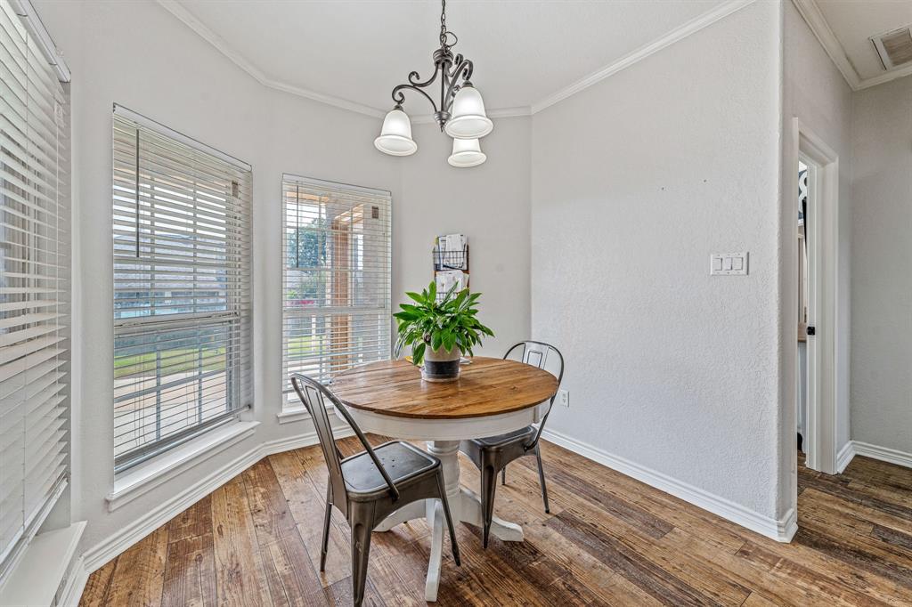 112 Blue Ribbon Lane Stephenville, TX 76401 - Photo 10 of 31 a dining room with wooden floor a chandelier a wooden table and chairs