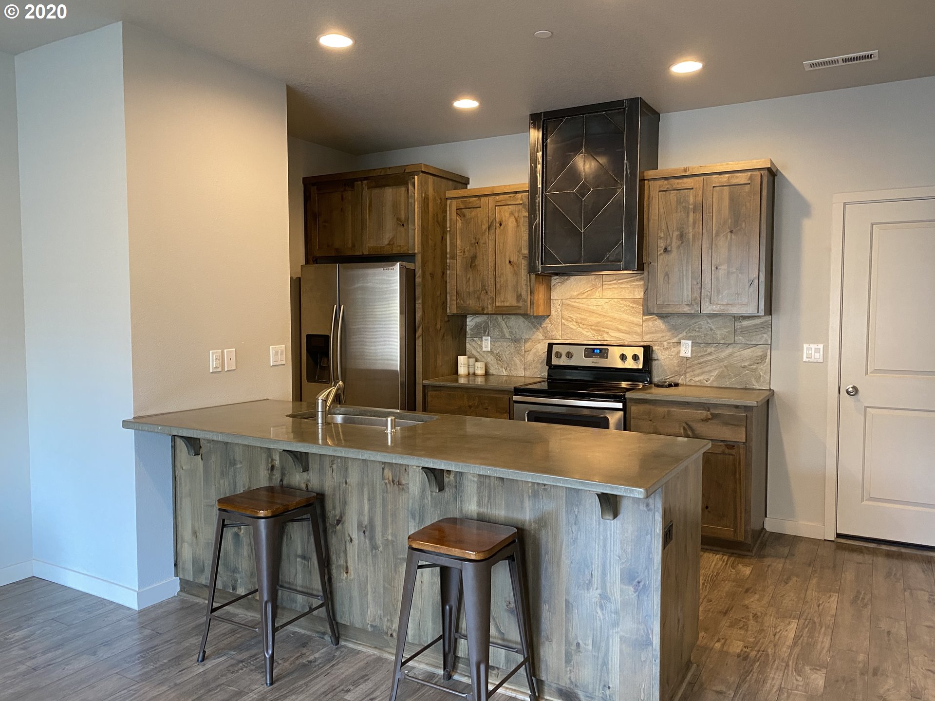 161 North 44th Place Ridgefield, WA 98642 - Photo 6 of 32 a kitchen with kitchen island granite countertop wooden cabinets and a refrigerator