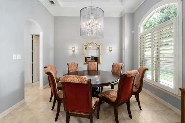 a view of a dining room with furniture a chandelier and a window