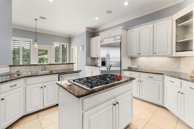 a kitchen with stainless steel appliances granite countertop a stove a sink and white cabinets