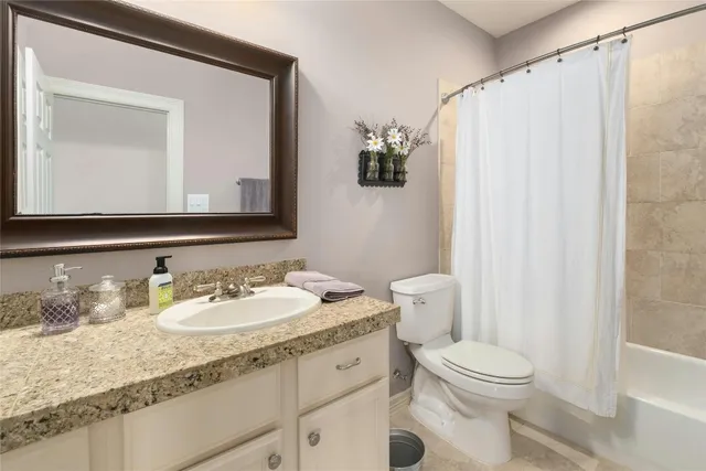 a bathroom with a granite countertop sink mirror vanity and toilet