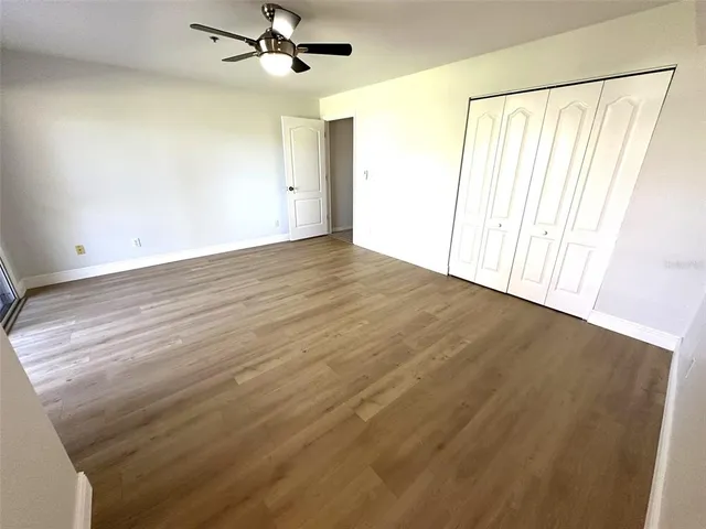 an empty room with wooden floor fan and windows