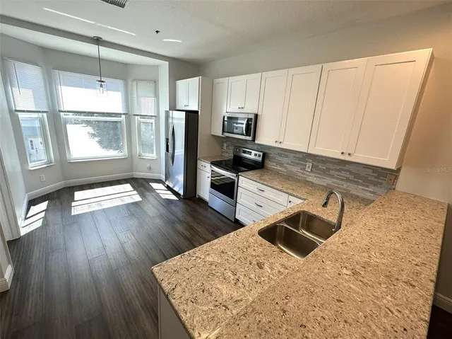 a kitchen with stainless steel appliances wooden floors wooden cabinets a refrigerator and a sink