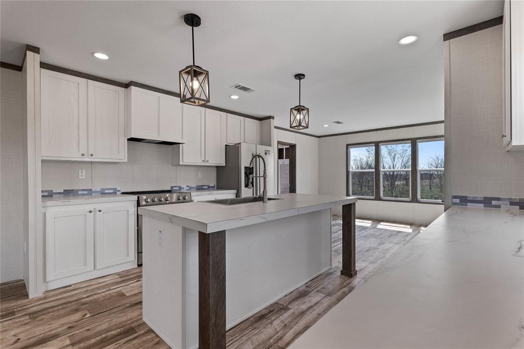3924 Sandusky Road Whitesboro, TX 76273 - Photo 7 of 22 Kitchen with light countertops, stainless steel appliances, hanging light fixtures, white cabinets, and light wood-style flooring