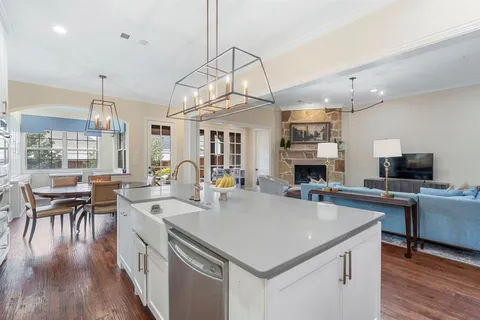 a kitchen with stainless steel appliances a stove a sink a refrigerator and chairs