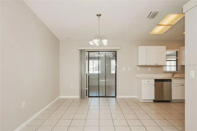 a view of an empty room with window and kitchen view